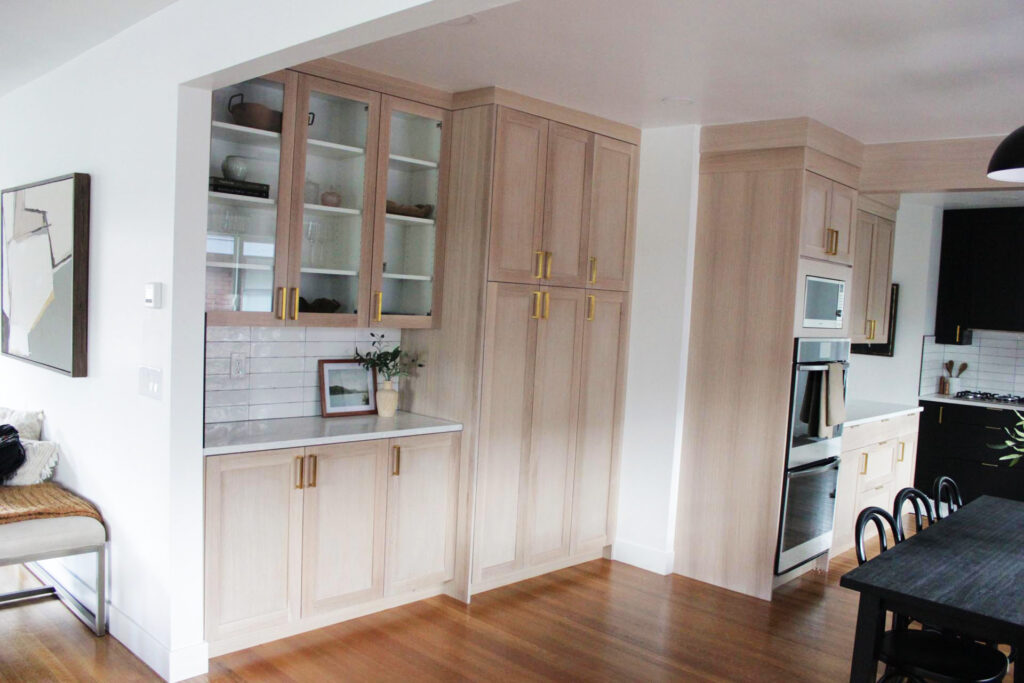 Custom-built walnut kitchen cabinets with shaker-style doors and brass hardware in a modern Utah home.